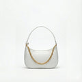 White crocodile-textured shoulder bag with gold chain detail on plain background