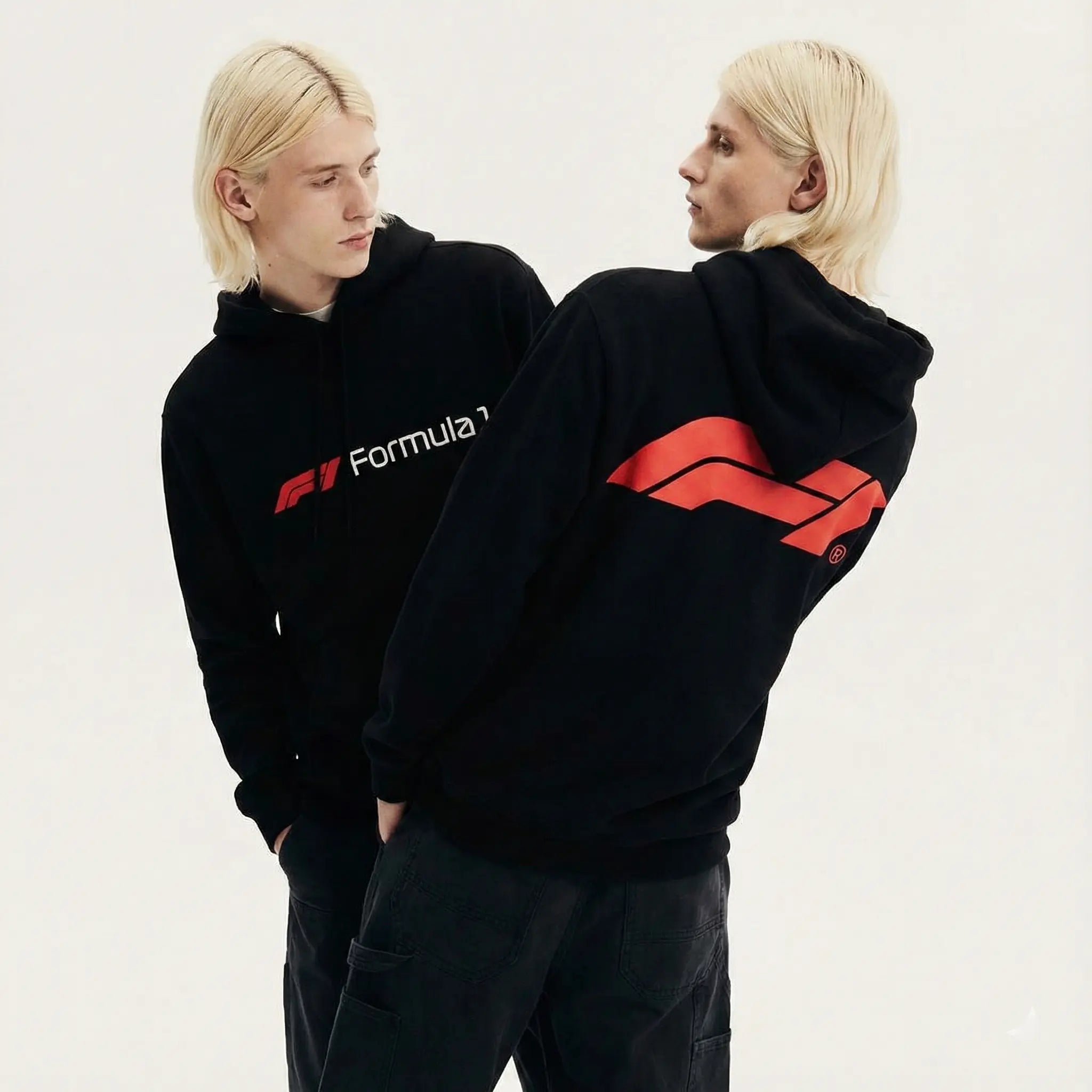 Two models wear black Formula 1 hoodies with bold red logo and streetwear style.