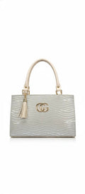 Silver structured handbag with gold accents, cream handles, tassel charm, and wavy textured design