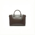 Dark brown leather handbag with top handles and butterfly charm on plain white background