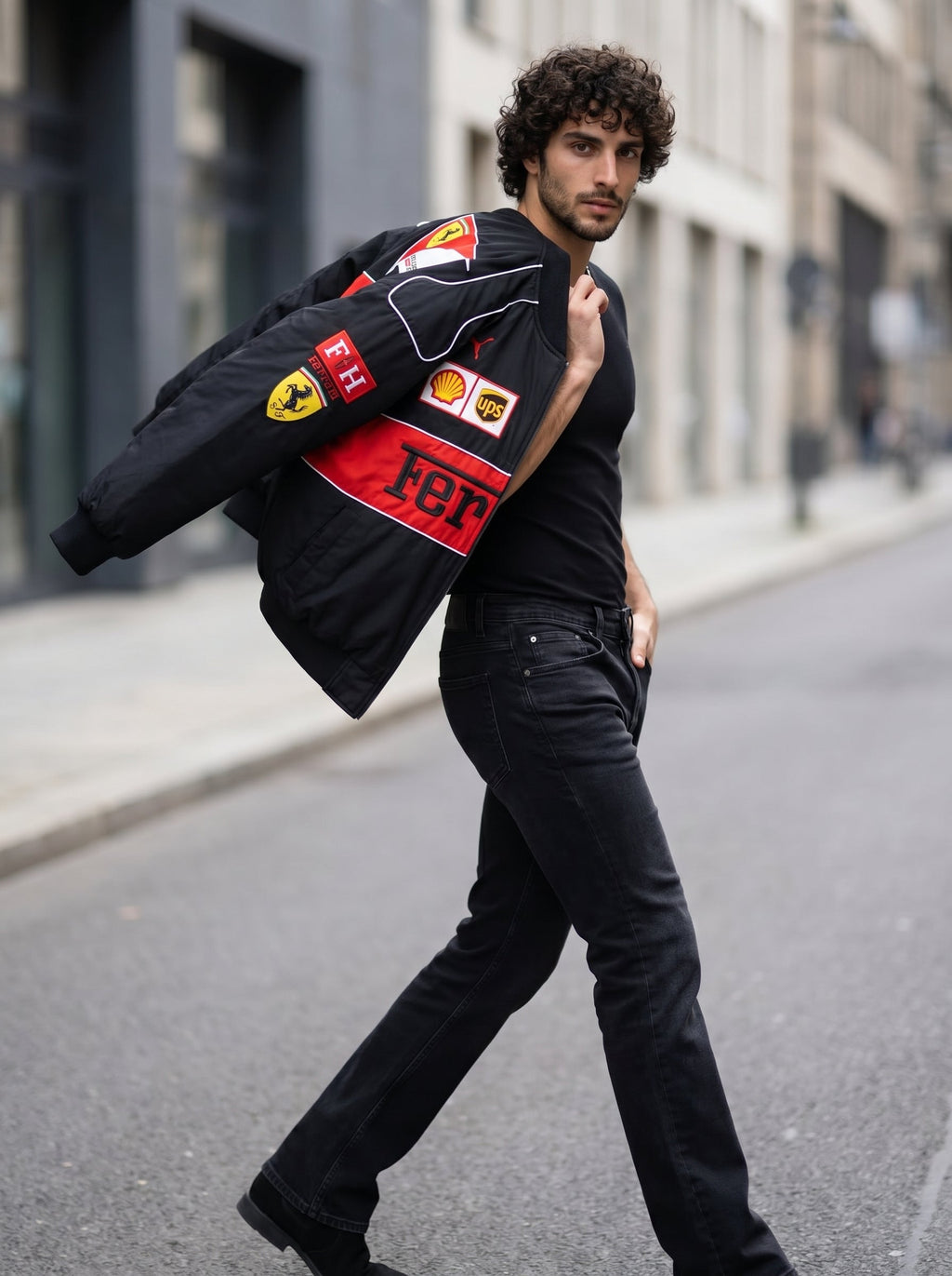 Editorial streetwear shot of a male model walking with the Eclatte Ferrari Racing Jacket draped over his shoulder, showing the red logo patches.