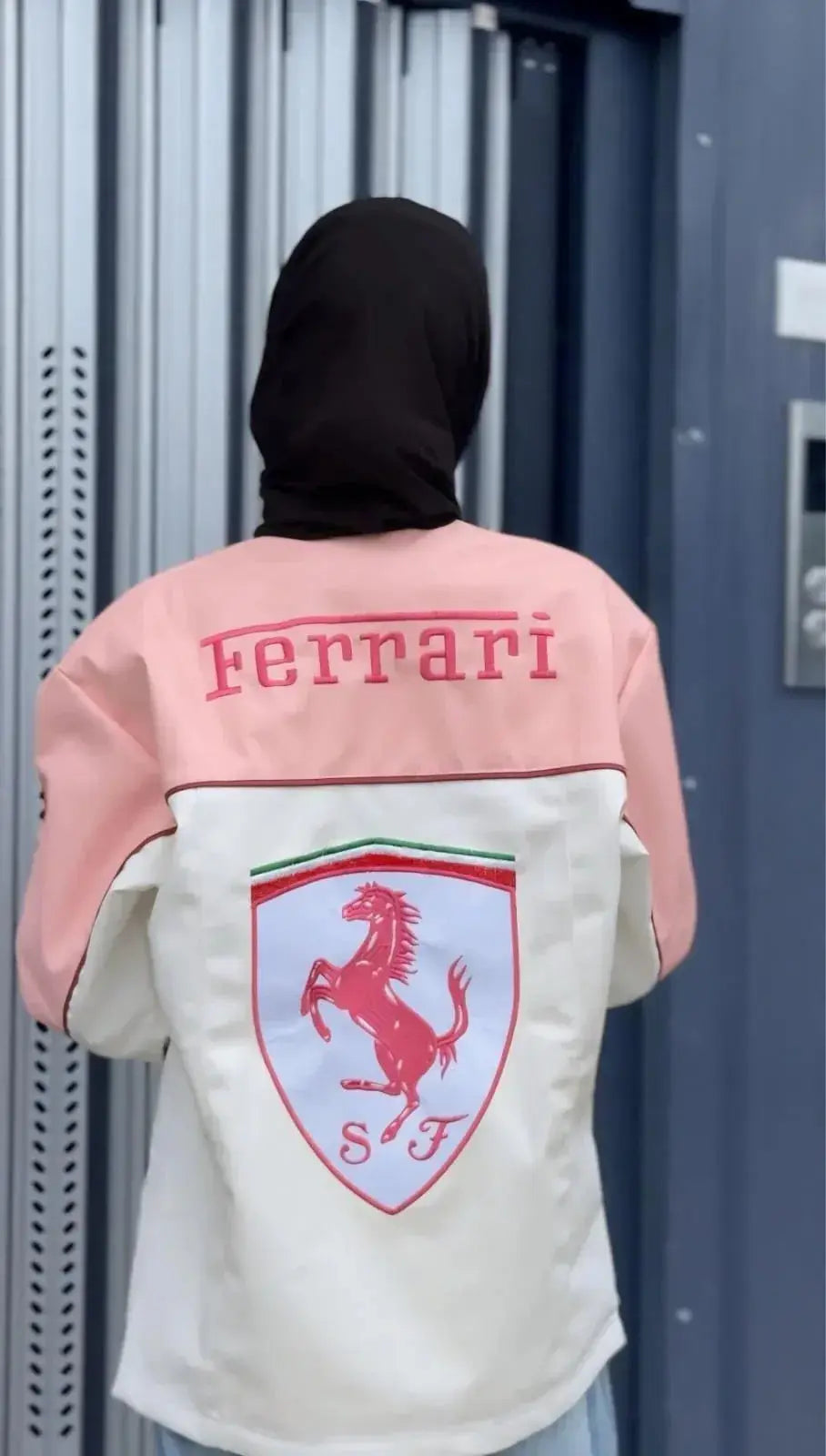 Back view of person in pink and white Ferrari logo streetwear jacket, modern urban style